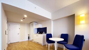 A modern apartment with a wooden floor, a kitchen area, and a dining space with two blue chairs and a white table. - Orbi City/Two Rooms Apt./27 Floor/Sea - Mout. View (Batumi)