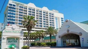 A large hotel with multiple floors, a prominent entrance with a palm tree, and a sign indicating it is a hotel and suites.