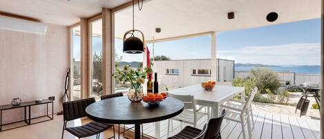 A modern dining area with a round table, black chairs, and a hanging light fixture.