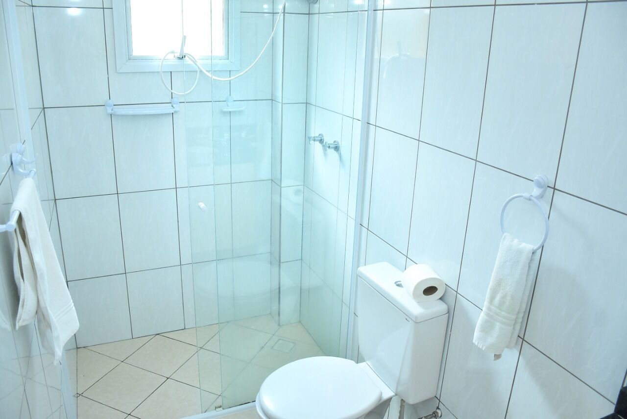 Een kleine, witte badkamer met een toilet, een douchecabine en een handdoekrek.
