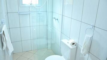 Een kleine, witte badkamer met een toilet, een douchecabine en een handdoekrek.