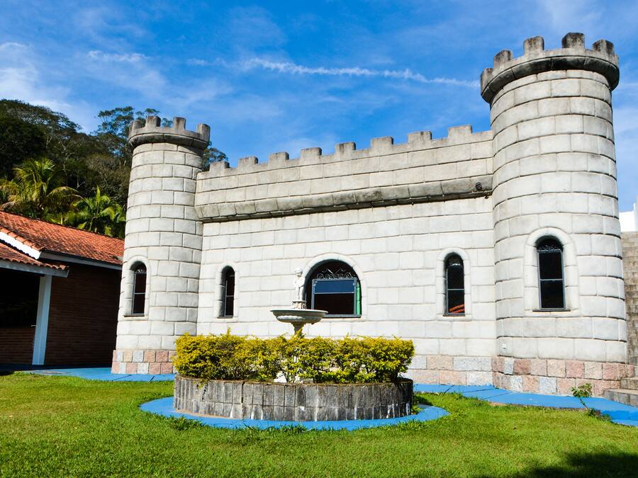 Un edificio de estilo castillo con un patio central, una fuente y una escalera que conduce a la entrada.