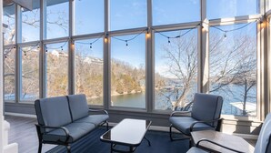 Ein Zimmer mit großen Fenstern, einem blauen Sofa, einem kleinen Tisch und einem Stuhl.