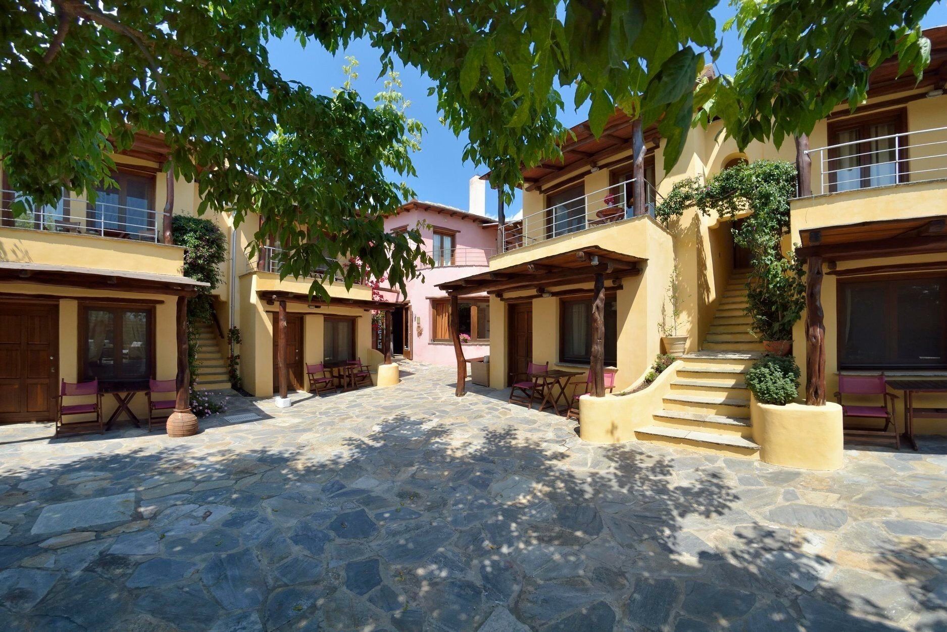 Un patio con suelo de piedra, mobiliario de madera y una escalera que sube a un nivel superior.