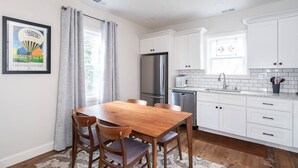 Eine moderne Küche mit weißen Schränken, einem Edelstahl-Kühlschrank und einem Holzespeisetisch mit Stühlen.