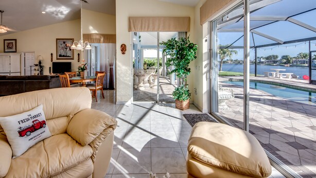 A spacious living area with a large window overlooking a pool and outdoor seating.