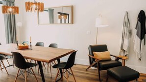 A modern dining area with a wooden table, black chairs, and a chandelier.