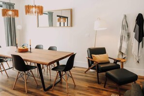 Un espace de salle à manger moderne avec une table en bois, des chaises noires et un lustre.