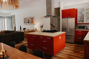 Een moderne keuken met rode kastjes, een roestvrijstalen koelkast en een houten eettafel.