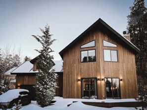 Une maison moderne en bois, dotée d’une grande porte d’entrée et d’un garage apparent.