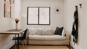 A minimalist living room with a sofa, a dining table, and a chair.