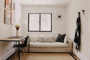 Ein schlicht eingerichtetes Wohnzimmer mit einer Couch, einem Esstisch und einem Sessel.