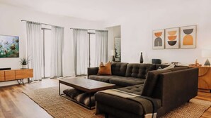 A modern living room with a sectional sofa, a coffee table, and a large window with curtains. - Yuhaaviat House | Walk to restaurants - Dogs OK (Big Bear Lake)