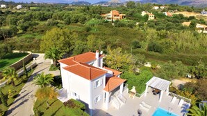 A large house with a swimming pool, surrounded by lush greenery and a hilly landscape. - Seawave Villa (Καραβαδος)
