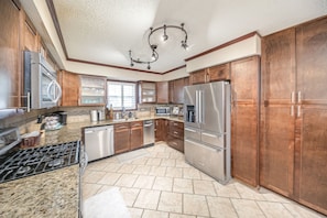 A modern kitchen with granite countertops, stainless steel appliances, and wooden cabinets.