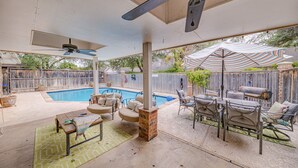 Un jardin avec une piscine, des meubles de patio et un ventilateur de plafond.