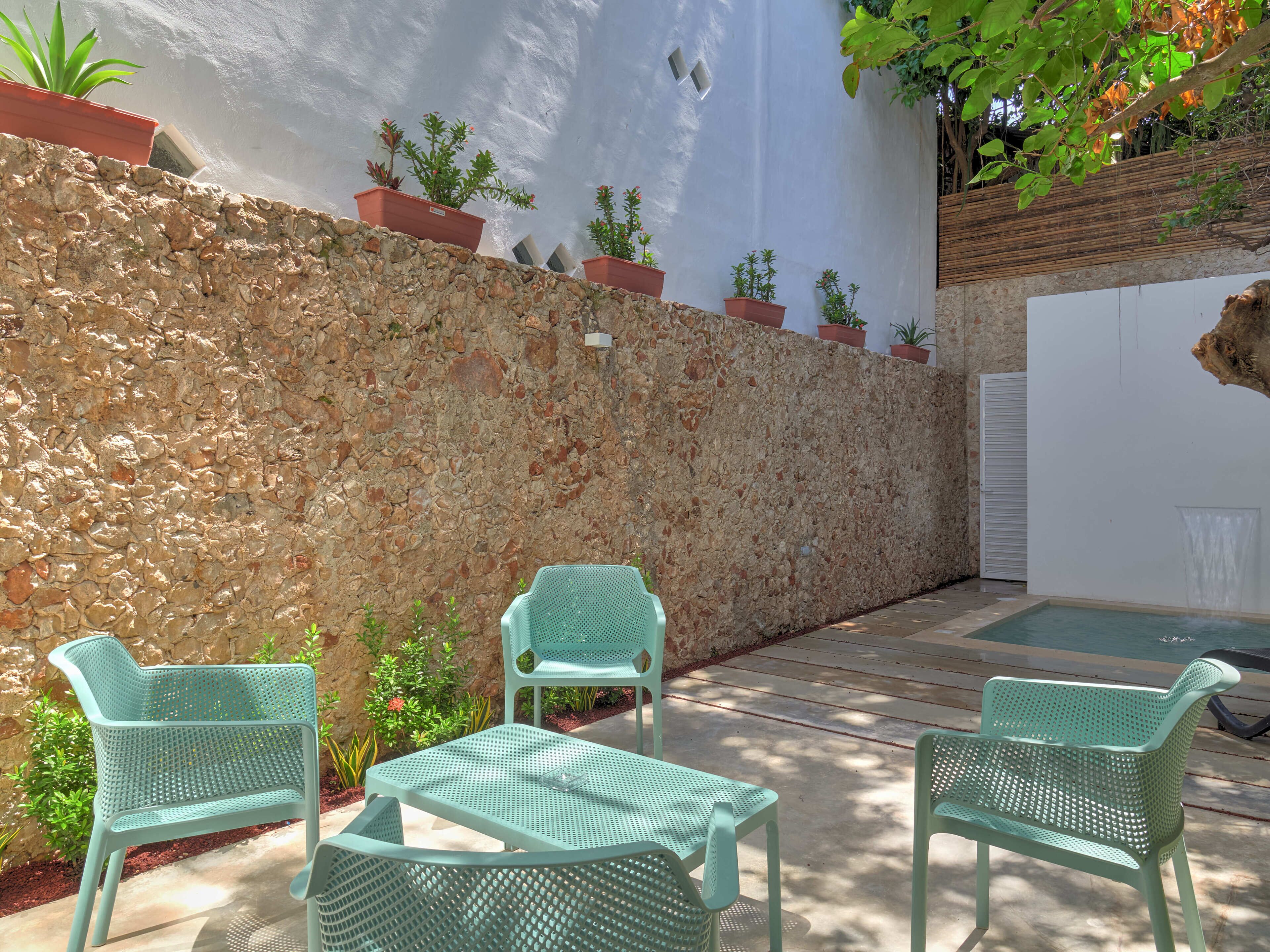 A patio area with stone walls, potted plants, and outdoor furniture.