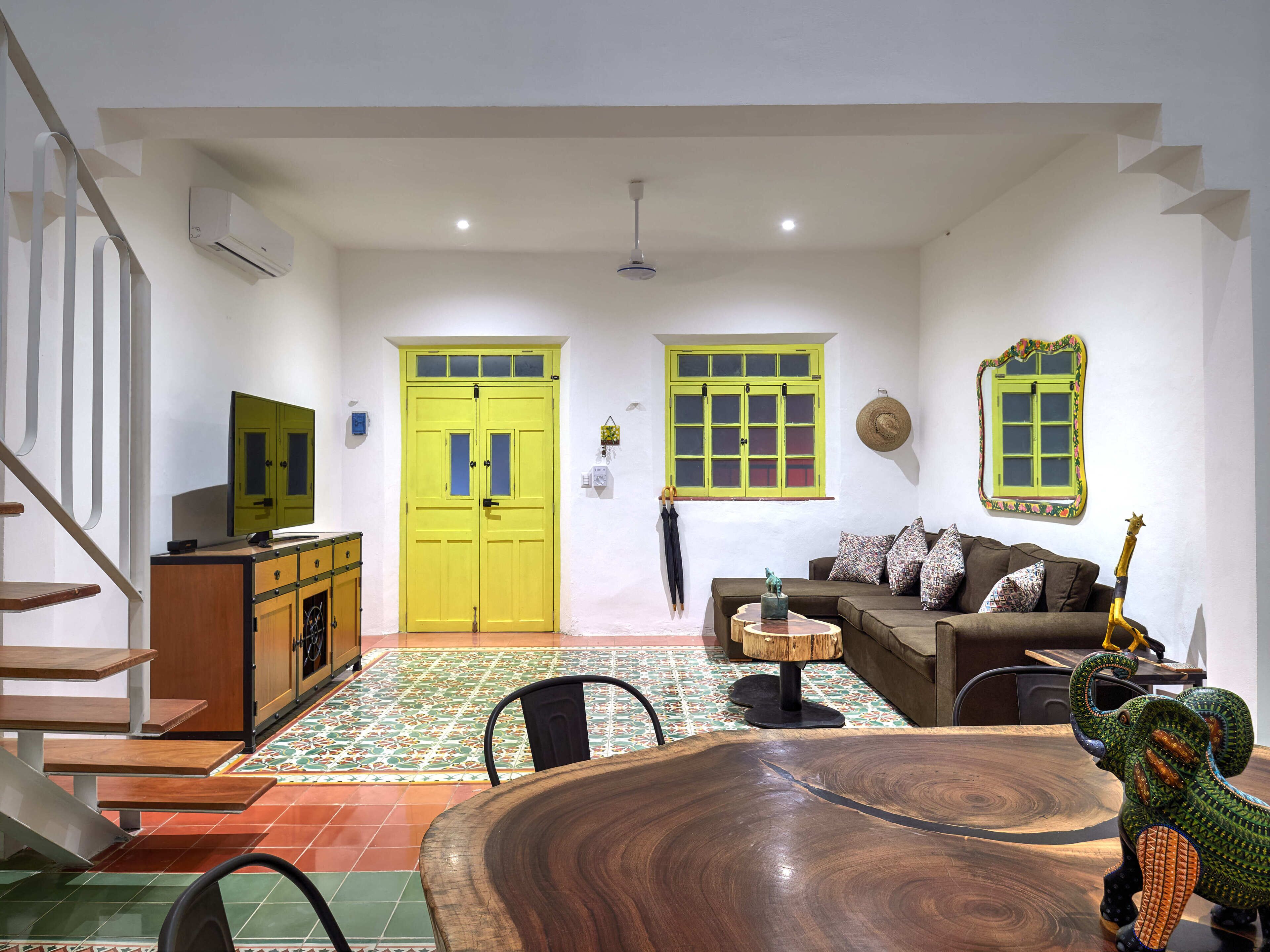 A spacious living room with a wooden dining table, a sofa, and a TV.