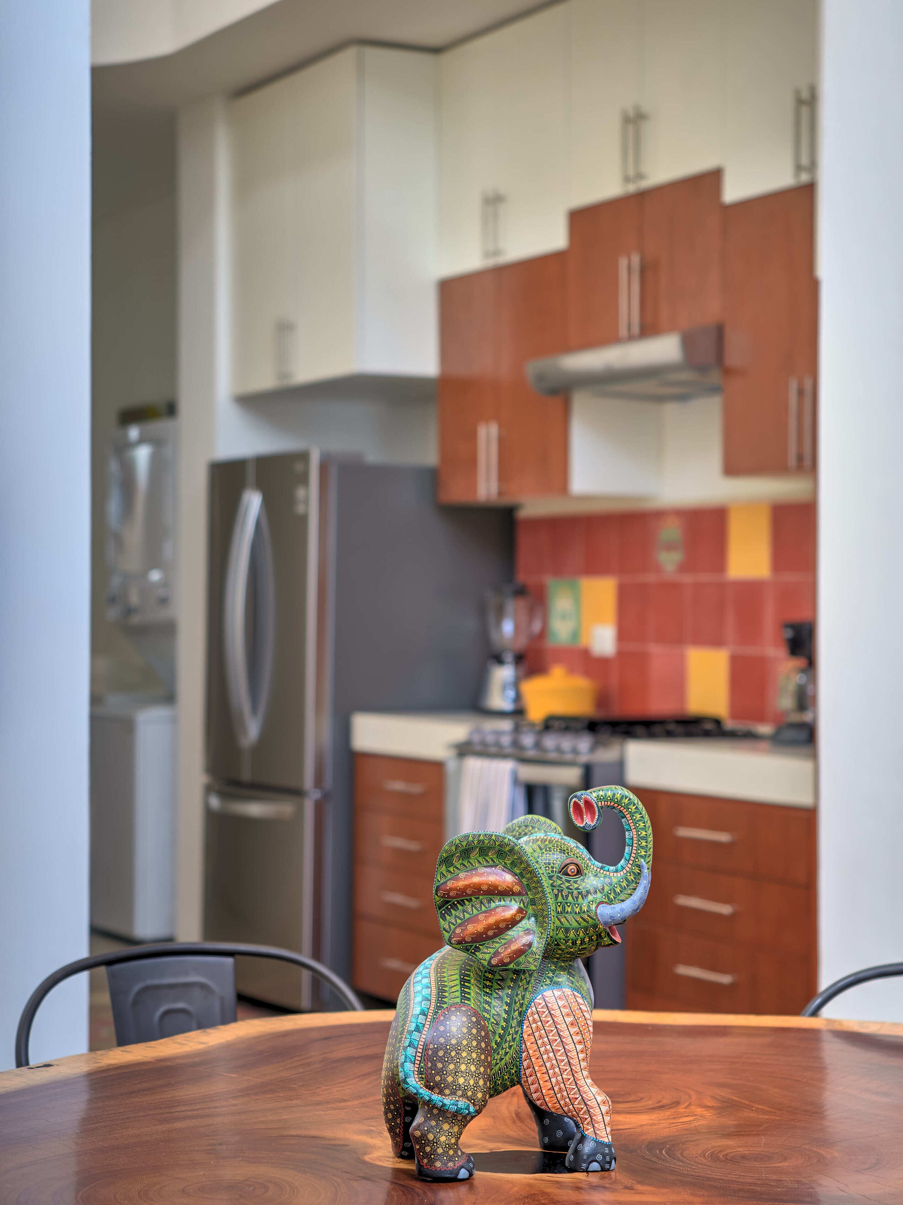 A dining table with a colorful elephant sculpture.