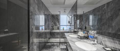 Un baño moderno con ducha de vidrio, dos lavamanos y un espejo grande.