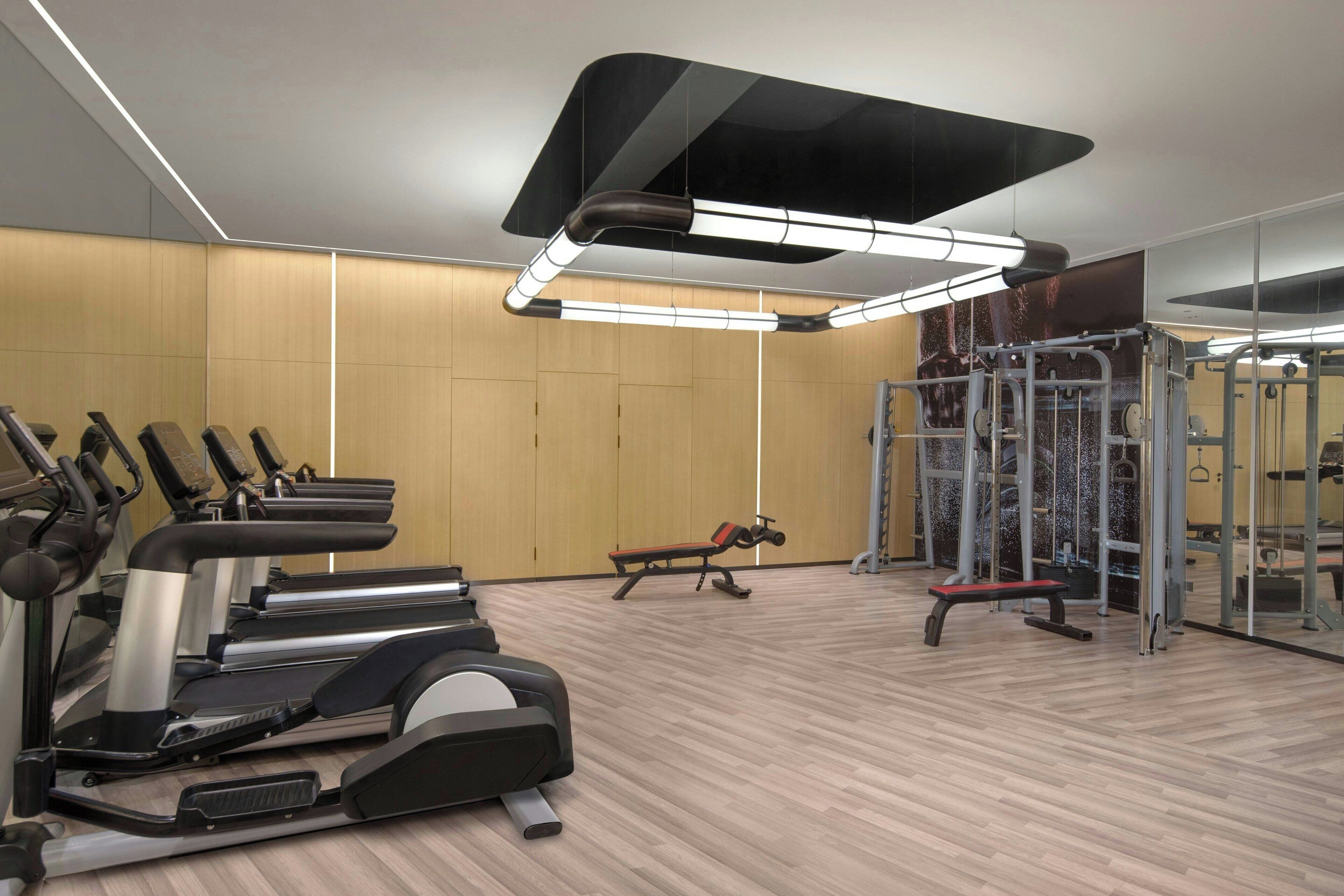 A gym with treadmills, a bench, and weightlifting equipment.
