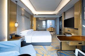 Relax in a spacious room with a large bed, flat-screen TV, and desk area.
