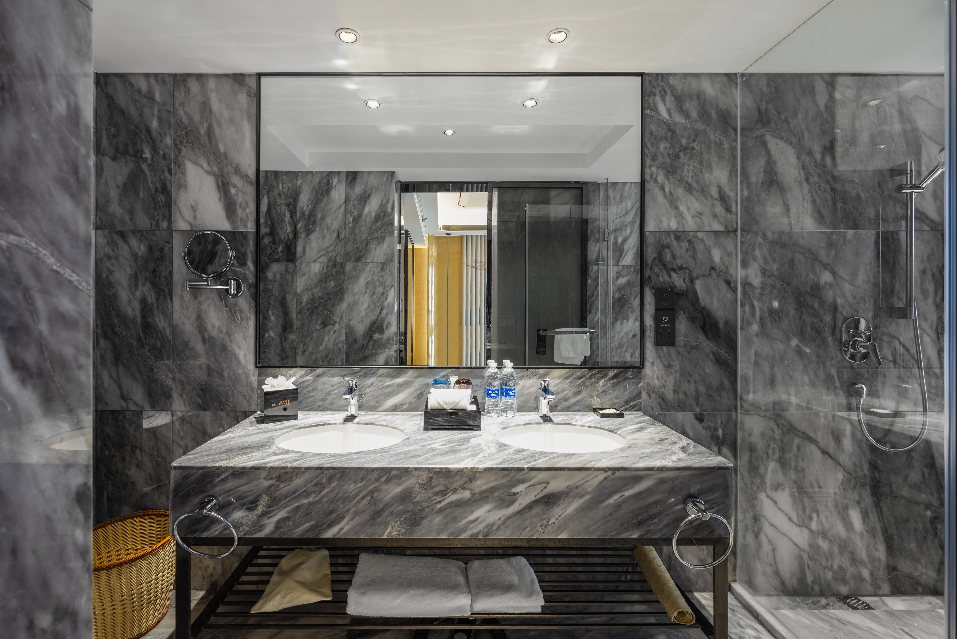 A modern bathroom with two sinks, a large mirror, and a glass shower enclosure.