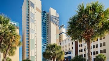 A hotel with multiple floors, a prominent 'Courtyard SpringHill Suites' sign, and palm trees in the foreground.