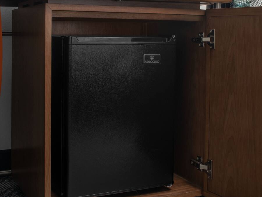 A black refrigerator with the brand 'ABSOCOOL' in a wooden cabinet.