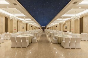 A banquet hall with round tables and chairs, a starry ceiling, and chandeliers. - Jing Cheng Hotel (Jiashan)