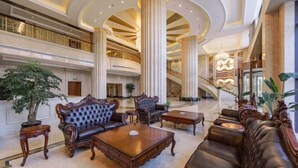 Un hall espacioso con techos altos, amplias columnas y una imponente escalera.