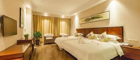 A hotel room with a large bed, a desk, a TV, and a window with curtains.