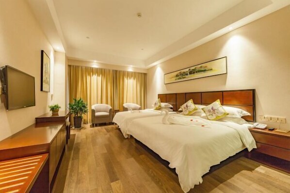 Una habitación de hotel con una cama grande, un escritorio, un televisor y una ventana con cortinas.