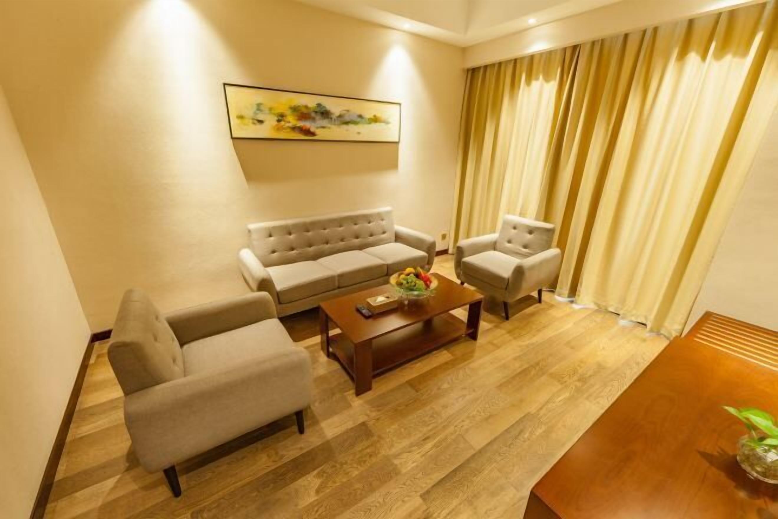 A living room with a sofa set, a coffee table, and a painting on the wall.