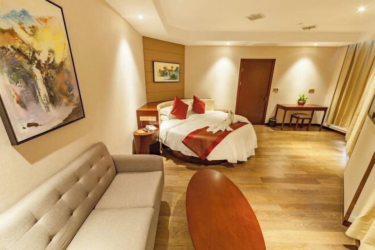 Una habitación de hotel con cama, sofá, escritorio y un cuadro en la pared.