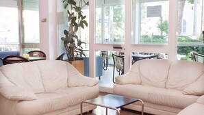 A room with two cream-colored sofas, a small table, and a potted plant.