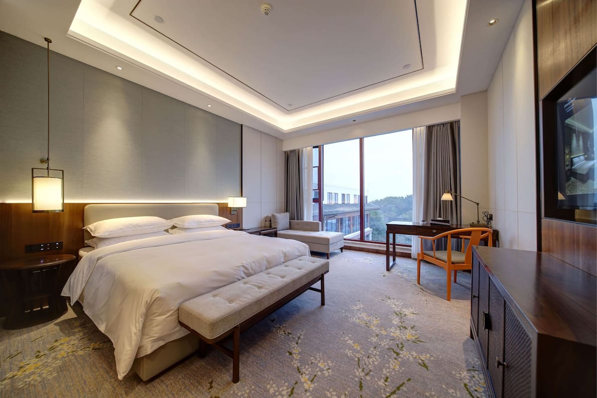 Ein modernes Hotelzimmer mit einem großen Bett, einem Schreibtisch und Blick auf die Stadt.
