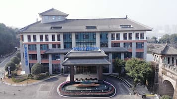 A hotel with a traditional architectural style, featuring a central courtyard with a fountain and a modern glass facade.