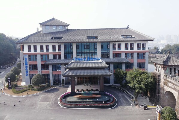 A hotel with a traditional architectural style, featuring a central courtyard with a fountain and a modern glass facade.
