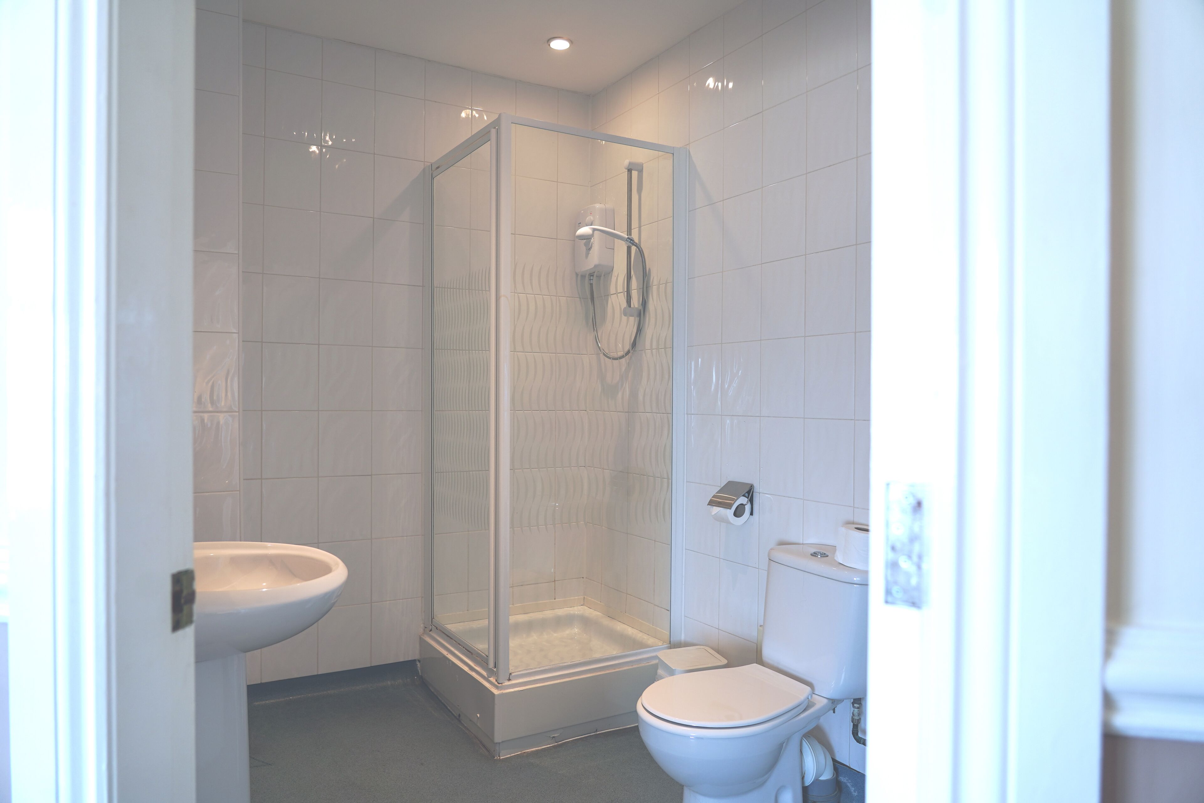 A bathroom with a shower enclosure, toilet, and sink.