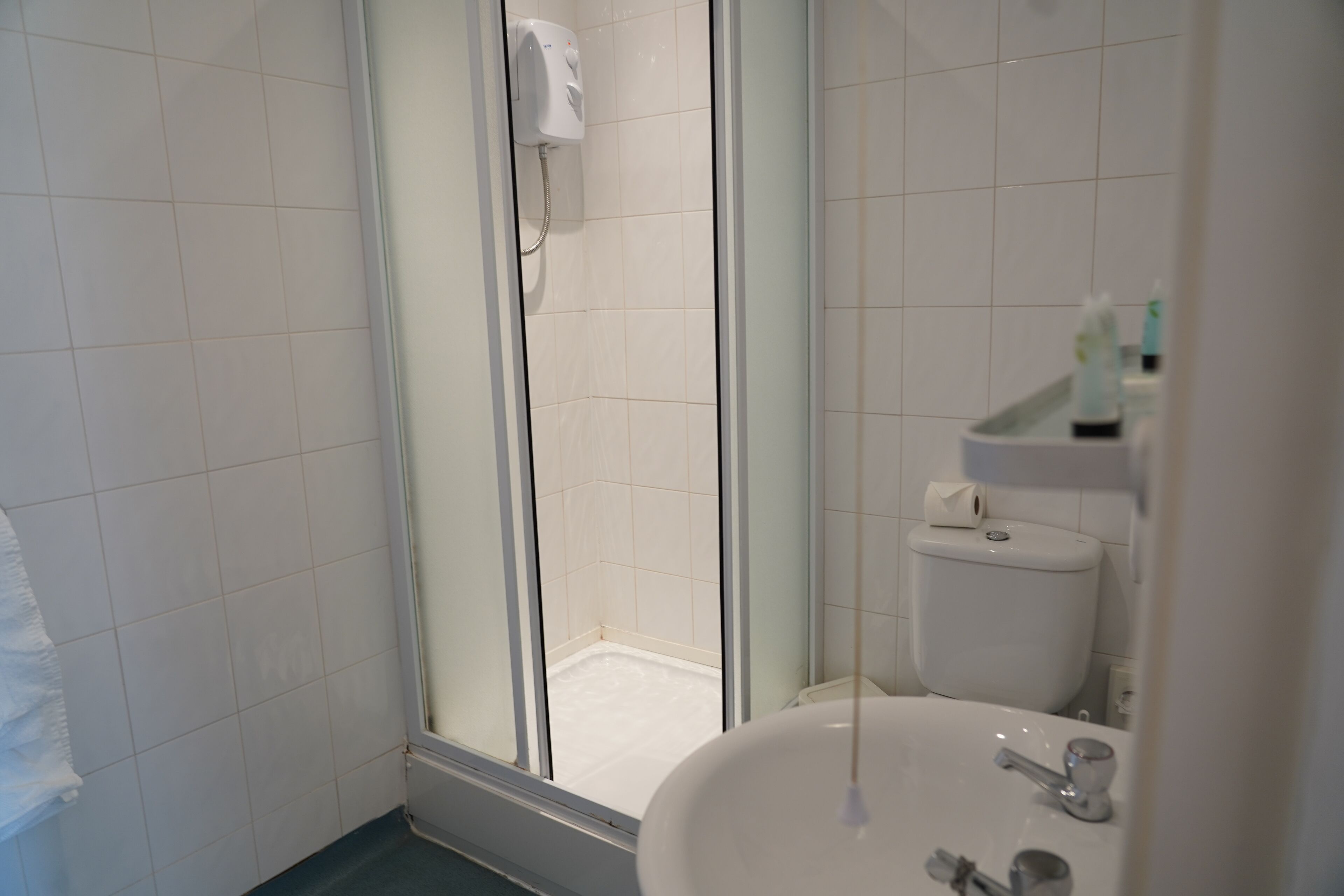 Un bagno con box doccia in vetro, un lavandino bianco e un water.