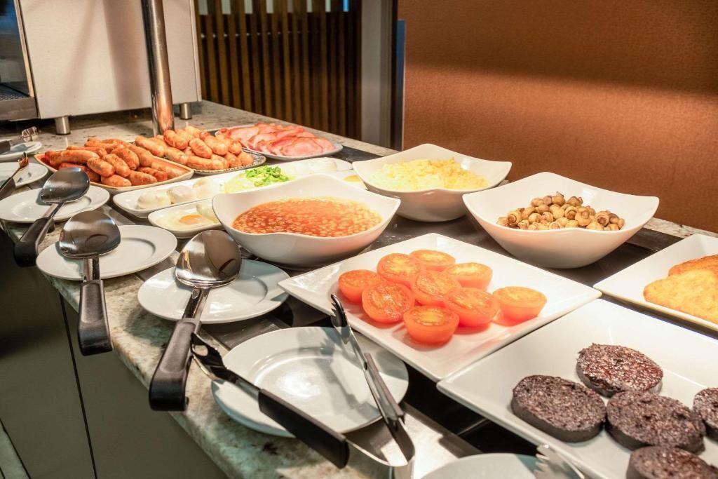 A buffet table with various food items including sliced tomatoes, nuts, and other dishes.