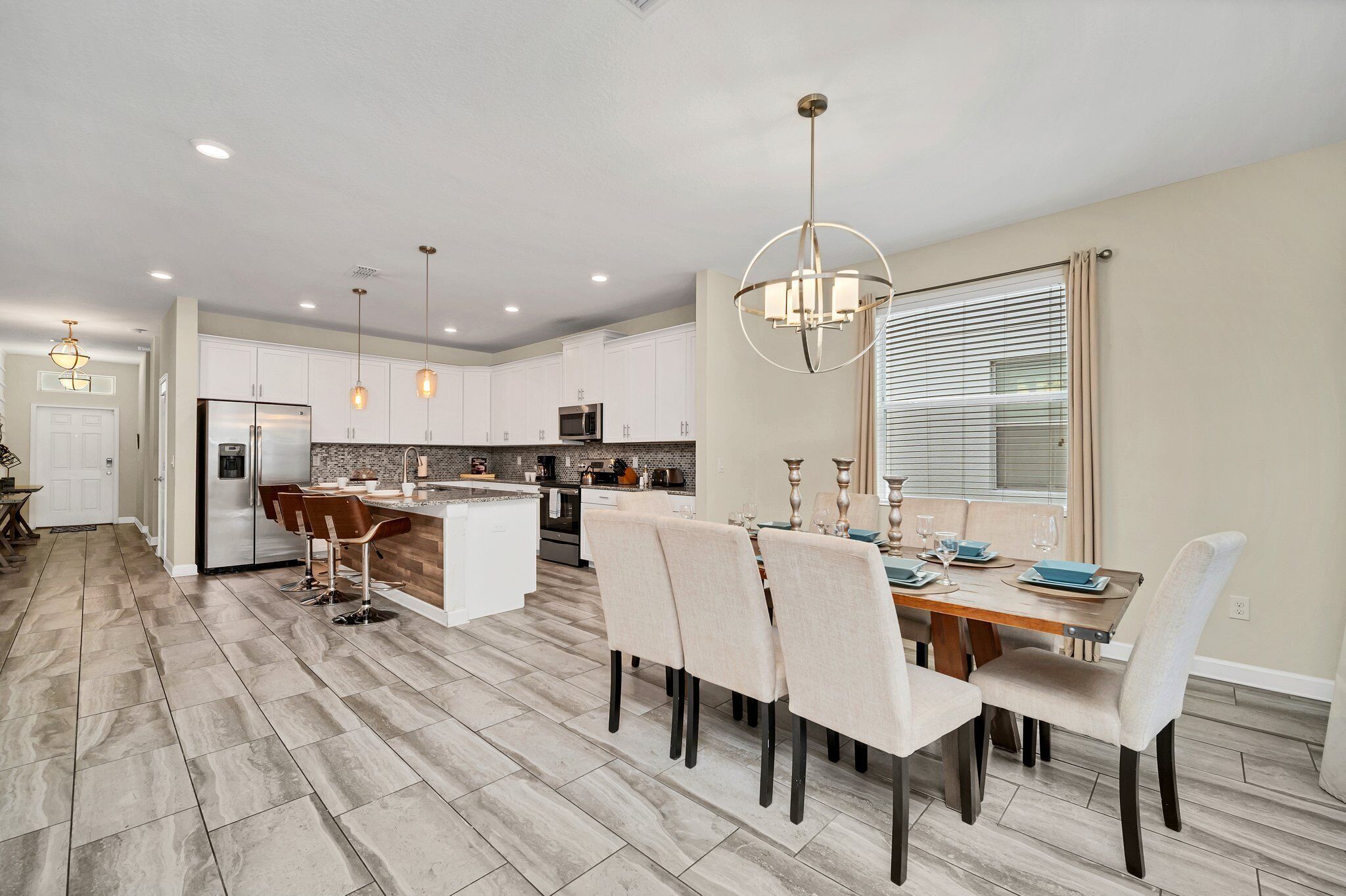 A modern kitchen with white cabinets, a central island, and pendant lighting.