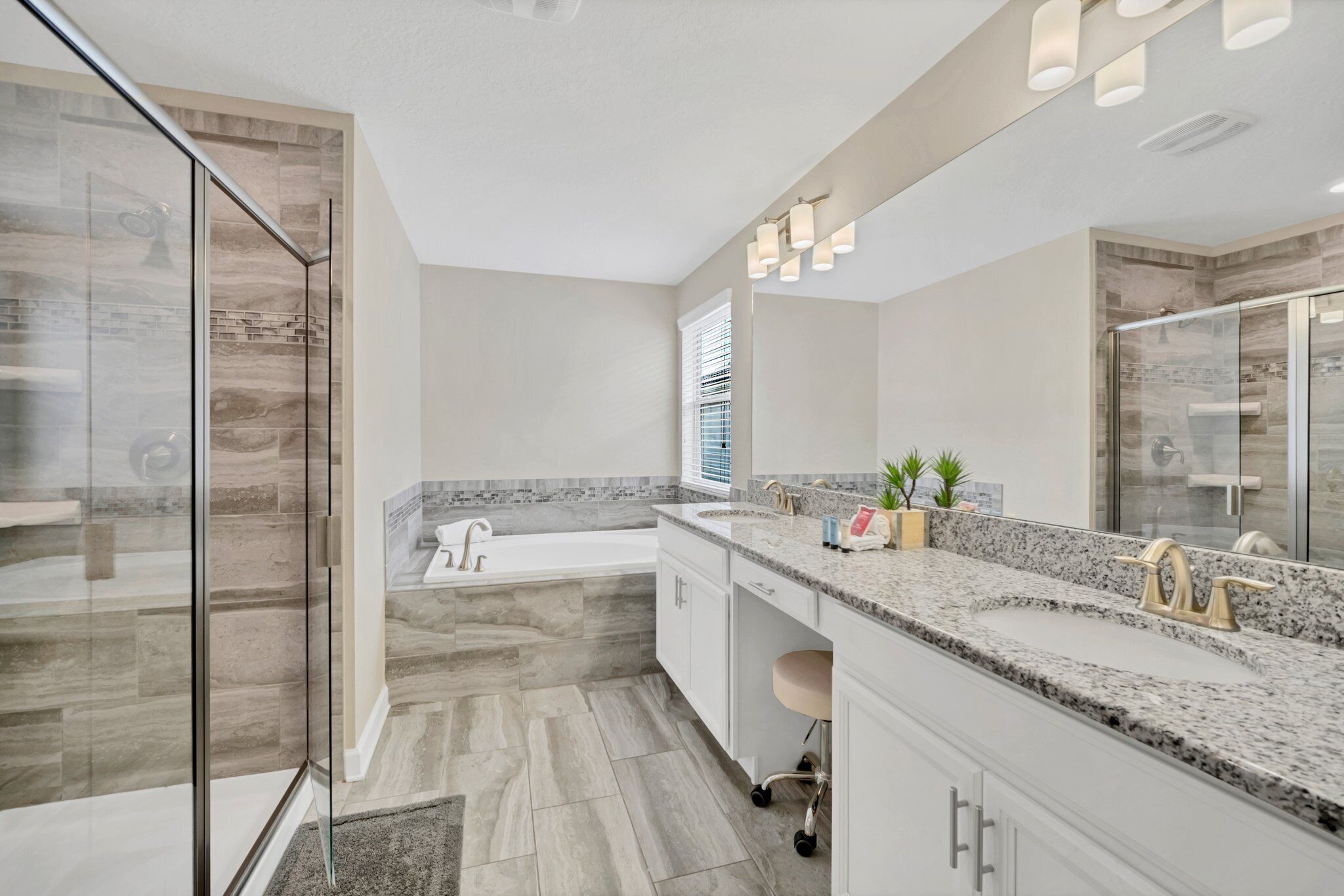 Une salle de bain moderne dotée d’une douche à parois de verre, d’une baignoire sur pieds et d’un meuble-lavabo avec un plan de travail en granit.