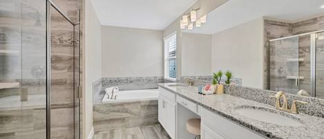 Une salle de bain moderne dotée d’une douche à parois de verre, d’une baignoire sur pieds et d’un meuble-lavabo avec un plan de travail en granit.
