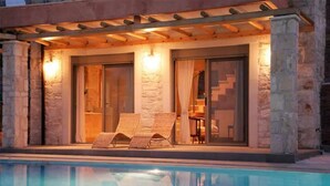 A poolside area with two lounge chairs and a covered seating area. - Thomais Villas Estate | Sea View & Private Pool (Agia Pelagia)