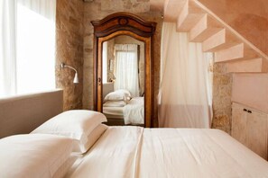 Un dormitorio con una cama grande, un armario de madera, un espejo y una escalera.