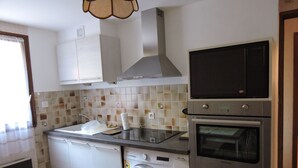 A kitchen with a washing machine, oven, and microwave. - T2 on the ground floor of our Villa, (Guillestre)