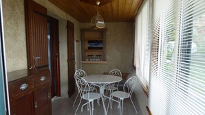 A dining area with a round table and four chairs, a wooden door, and a shelf with a painting. - T2 on the ground floor of our Villa, (Guillestre)