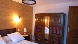 A wooden-paneled room with a bed, a nightstand, a lamp, and a wardrobe with a mirror. - T2 on the ground floor of our Villa, (Guillestre)